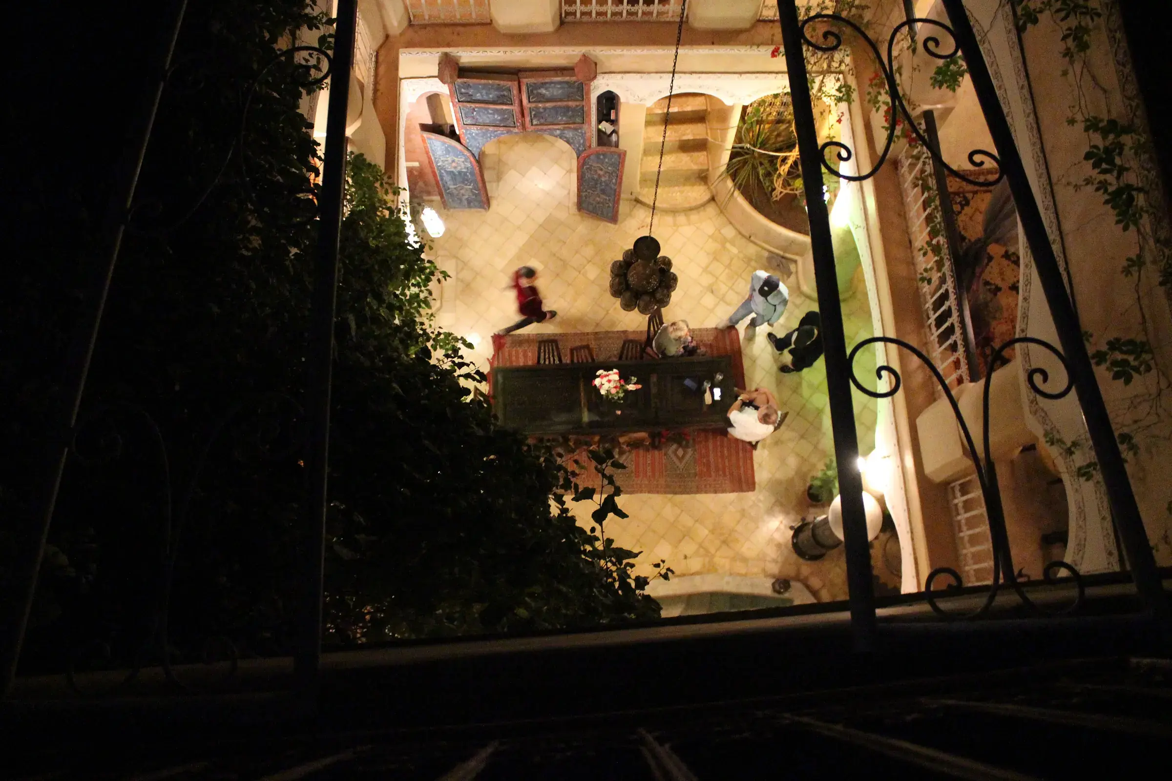 Patio de un riad de la medina visto desde la azotea, de noche, zellige y faroles encendidos