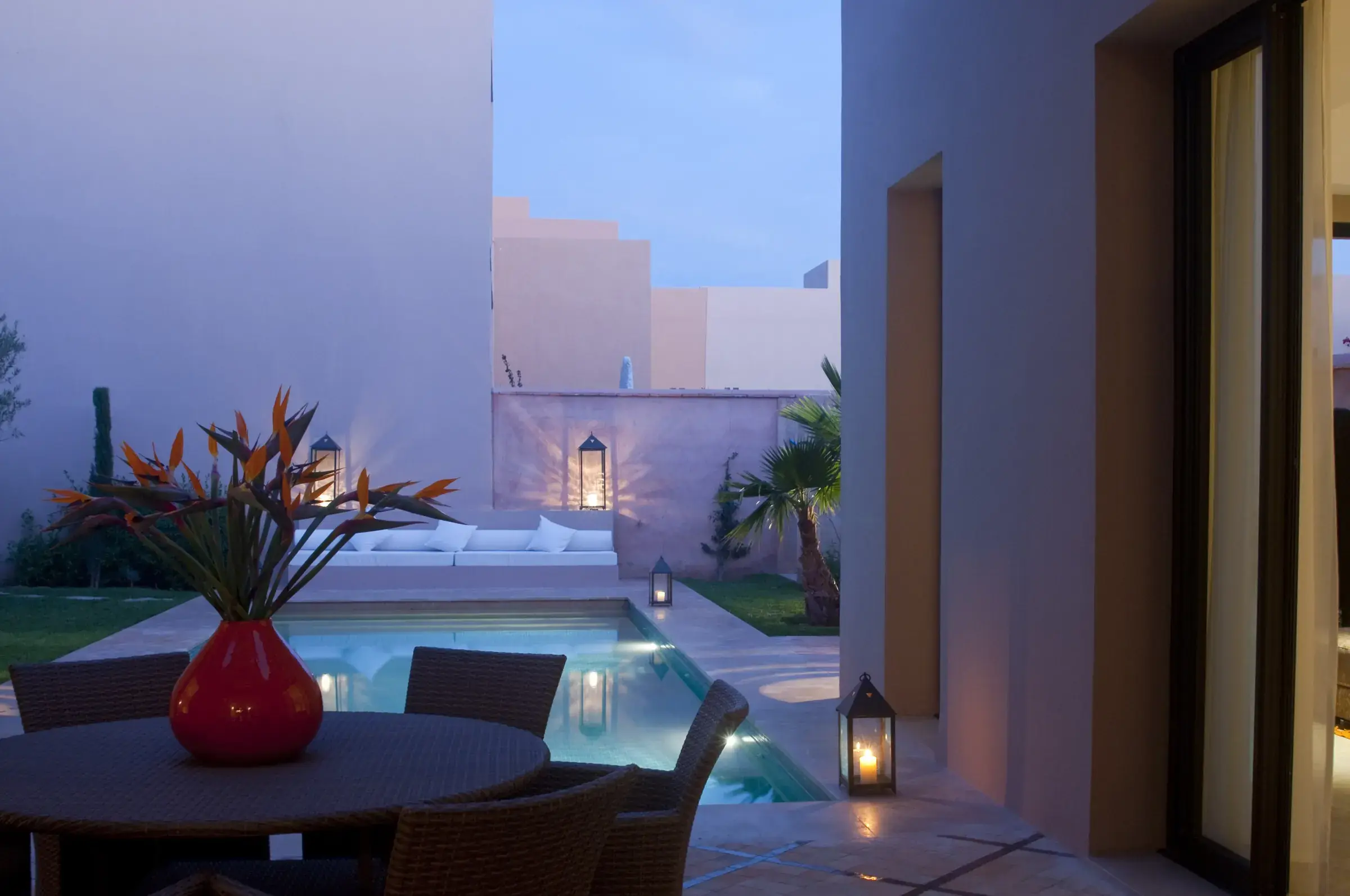 Terrasse d'une villa contemporaine à Marrakech, piscine éclairée au crépuscule